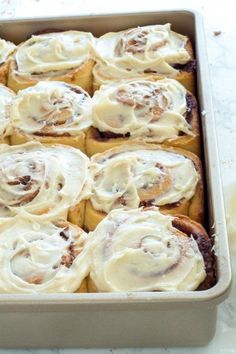 a pan filled with cinnamon rolls covered in icing