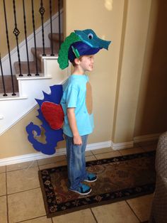 a young boy standing in front of a stair case wearing a paper hat with a dragon on it