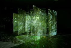 an art installation is shown in the dark with green light coming from it's sides