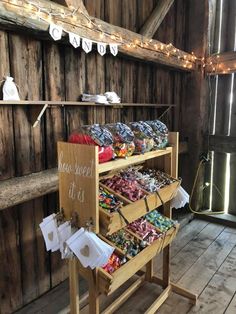 a wooden stand filled with lots of different types of candies on display in a barn