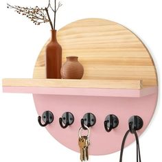 there is a pink shelf with black hooks on it and a vase in the background