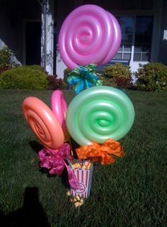 a bunch of balloons that are in the grass with some flowers on top of them