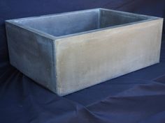 a square concrete planter sitting on top of a blue cloth covered surface with a black background