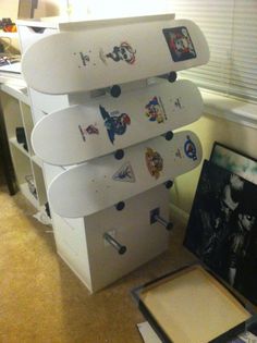 a stack of skateboards sitting on top of each other next to a box with stickers all over it