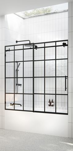 a white tiled bathroom with an open glass shower door and two faucets on the wall