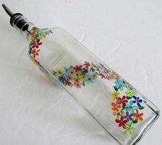 an empty glass bottle with colorful flowers painted on the side and a black metal cap