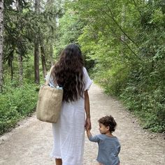 a woman walking down a dirt road holding hands with a small boy on the other side