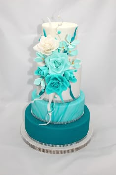 a three tiered blue and white wedding cake with flowers on the top, sitting on a silver platter