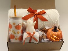 an open gift box with candles, towels and pumpkins