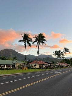 a street with palm trees and buildings on the side of it at sunset in hawaii