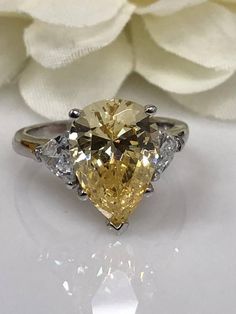 a fancy yellow diamond ring sitting on top of a white flower