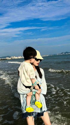 a woman holding a child on the beach