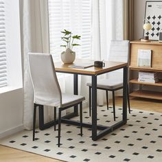 a dining room table with two chairs and a potted plant