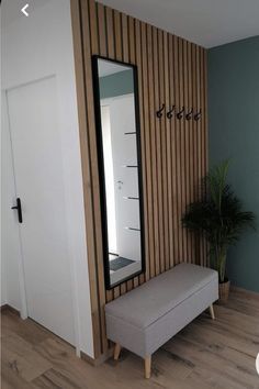 a bench sitting in front of a mirror on top of a wooden floor next to a plant