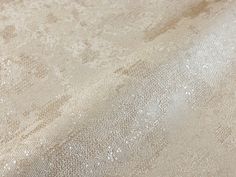 an upholstered fabric textured with white and silver glitters on a beige background