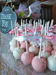 cake pops are arranged on a glass plate with pink and white candies in the middle