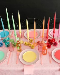 the table is set with colorful plates and candles