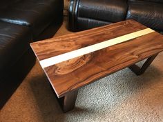 a wooden table sitting on top of a carpeted floor next to a black couch