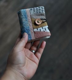 a hand holding a small patchwork wallet