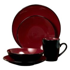 a red and black dinnerware set on a wooden table with a cup, saucer and plate