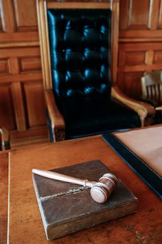 a wooden desk with a black chair in the background and a marble block on it