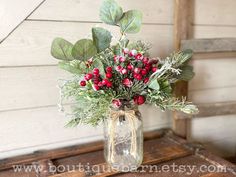 a vase filled with red berries and greenery