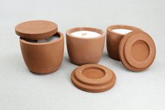 three clay pots and two candles on a table