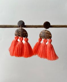 "Gorgeous pink tassel statement earrings. A trio of lovely coral pink tassels hang neatly from half-moon tropical coconut post earrings. The perfect Boho fringe coconut wood earrings for every day! Easy to layer and yet make a statement on their own. This Boho inspired pair showcases the natural beauty of the coconut and the beauty of tassels. The delicate playful design and detailed polished finish make these a one-of-a-kind. These sustainable earrings are thoughtfully crafted from re-purposed coconut shells found by the Pacific seashores of El Salvador.  Each piece is carefully crafted by our artisan partners in a fair trade environment.  We value the richness and beauty of nature and have transformed each piece into a piece of art.  Each pair is unique because coconut has its natural co Pink Beaded Tassel Earrings For Beach, Beach Dangle Chandelier Earrings With Tassels, Tassel Drop Earrings For Vacation, Vacation Tassel Drop Earrings, Orange Tassel Dangle Earrings, Orange Beaded Tassel Earrings As Gift, Red Tassel Earrings For Beach, Beach Macrame, Coconut Earrings