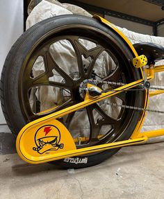 a yellow bike with black spokes and a skull on the front wheel is parked in a garage