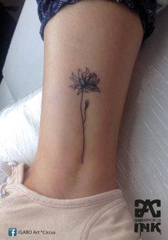 a woman's lower leg with a small flower tattoo on her left side ribcage