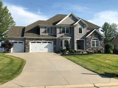 a large house with two garages and lots of grass