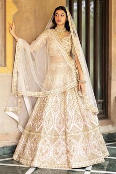 a woman in a white and gold lehenga