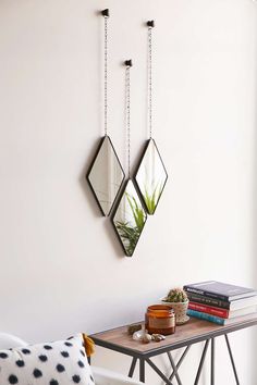 three mirrors hanging on the wall above a table with a plant and potted succulent