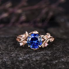 a blue ring sitting on top of a black stone table next to a purple flower