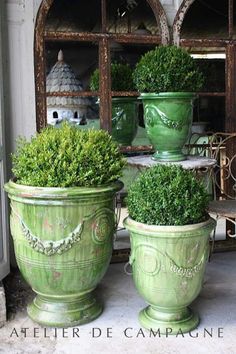 two large green planters sitting on top of a cement floor next to each other