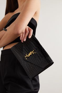 SAINT LAURENT's clutch has been made in Italy from glossy croc-effect leather in a slim, envelope shape and has enough space for your phone, cards and keys. Topped with the brand's iconic 'YSL' plaque, it comes with a detachable wristlet strap to free up your hands. Ysl Croc Bag, Ysl Uptown Pouch Outfit, Ysl Clutch Bag, Clutch Purse Outfit, Ysl Clutch Outfit, Ysl Envelope Clutch, Purse List, Clutch Outfit, Saint Laurent Clutch