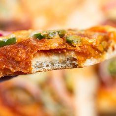 a close up of a piece of pizza on a person's hand holding it