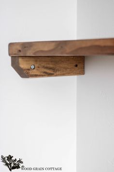 a close up of a wooden shelf on a wall with a plant in the corner