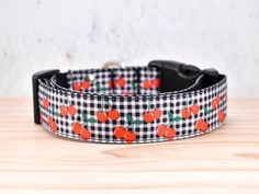 a black and white checkered dog collar with orange pumpkins on it, sitting on top of a wooden table