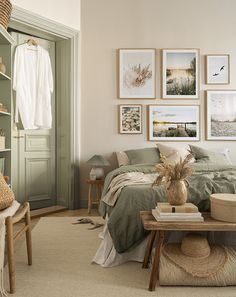 a bedroom with green walls and pictures on the wall above the bed, along with a wicker chair