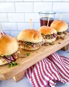 three pulled pork sliders on a cutting board with toothpicks in the middle