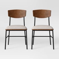 two chairs with wooden backrests and white upholstered seat cushions, one is black