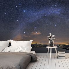 a bed sitting on top of a wooden floor under a night sky filled with stars