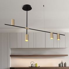 a kitchen with white cabinets and black lights hanging from the ceiling over the stove top