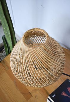 a wicker basket sitting on top of a wooden table next to a cactus plant