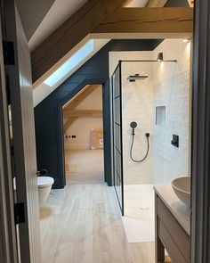 an attic bathroom with white tile and wood flooring is seen through the open doorway