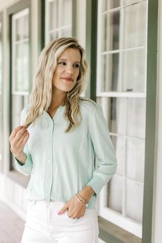 Model wearing a button up mint green cardigan with 3/4 sleeves. Spring Workwear Cardigan With Buttons, Spring Workwear Cardigan With Button Closure, Green Relaxed Fit Cardigan For Spring, Green Relaxed Fit Blouse For Layering, Spring Casual Cardigan With Button Cuffs, Casual Green Blouse For Layering, Green Cotton Blouse For Layering, Casual 3/4 Sleeve Outerwear For Day Out, Casual Outerwear With 3/4 Sleeve For Day Out