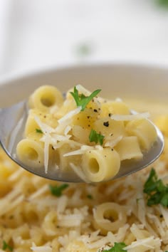 a spoon full of pasta with parmesan cheese and parsley