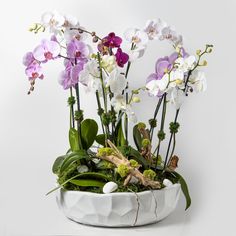 a white vase filled with lots of purple and white flowers