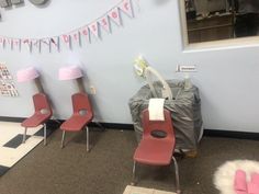 three red chairs sitting next to each other in front of a wall with bunting